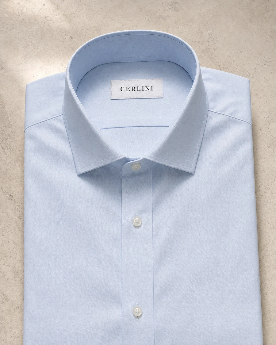 The Partner in light blue, a Cerlini business shirt folded to show its collar and placket.