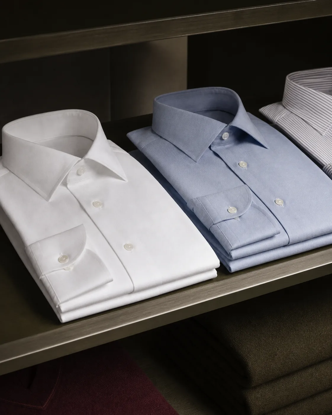 Folded white and blue premium shirts arranged on a shelf.